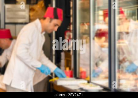 Unscharfer Koch mit osmanischem fez in einem Restaurant, das traditionelle osmanische Gerichte serviert. Stockfoto