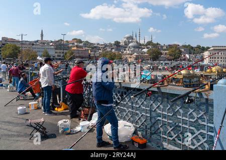 Istanbul, Türkei - 17. September 2023: Menschen fischen auf der Galata-Brücke und Moscheen im Hintergrund. Istanbul, Türkei. Stockfoto