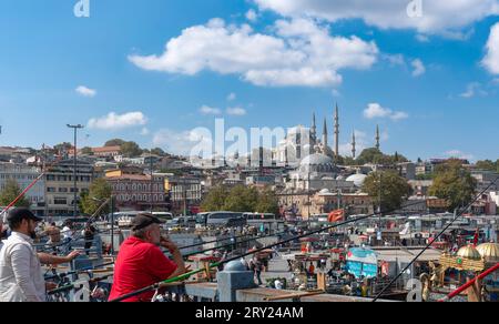 Istanbul, Türkei - 17. September 2023: Menschen fischen auf der Galata-Brücke und Moscheen im Hintergrund. Istanbul, Türkei. Stockfoto