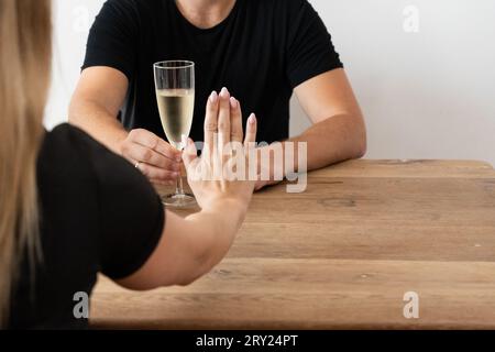 Ein nüchternes neues Jahr: Frau, die Alkohol abnimmt, mit Mineralwasser tröstet, NOLO, Enthaltsamkeit, Probleme mit Alkohol löst, Nein zu Drinks bei Social sagt Stockfoto