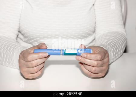 Weibliche Hände, die einen Insulinpen halten. Ozempic Insulin-Injektions-Pen oder Insulin-Patronen-Pen für Diabetiker. Medizinische Geräte für Diabeteskranke. Stockfoto