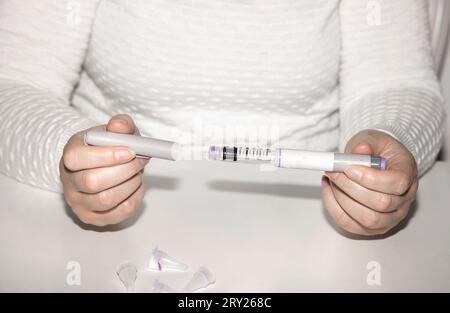 Weibliche Hände, die einen Insulinpen halten. Ozempic Insulin-Injektions-Pen oder Insulin-Patronen-Pen für Diabetiker. Medizinische Geräte für Diabeteskranke. Stockfoto