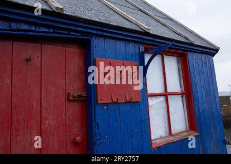 Ein Blick aus der Nähe auf einen hell bemalten rot-blauen Holzschuppen im Hafen von St. Abbs Stockfoto