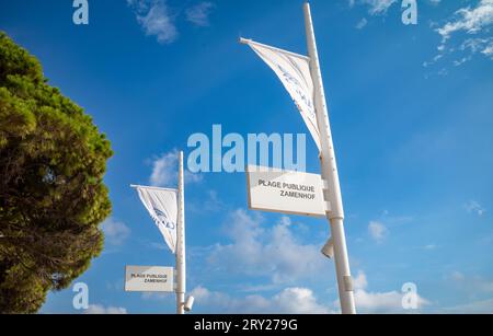 Flaggenmasten und Schilder für den öffentlichen Strand Zamenhof in Cannes an der Cote d'Azur in Südfrankreich. Stockfoto