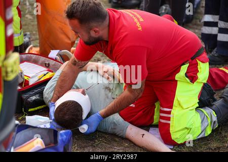 28. September 2023, Sachsen, Wiederau: Rettungssanitäter in Trainingsbandagen ein Mann, der ein Opfer eines Terroranschlags während einer Terrorübung darstellt. Rund 150 Auszubildende des Deutschen Roten Kreuzes, Samariter und Sankt-Johannes-Ambulanz aus Sachsen und Sachsen-Anhalt nehmen am Ende einer Trainingswoche an einer inszenierten Terrorsituation Teil. Es gab ein Attentat mit zahlreichen Opfern: Der Täter hat sich verwurzelt, Schüsse werden abgefeuert, es gibt Rauch, schwer bewaffnete und verhüllte Polizisten stürmen das Gebäude. Danach müssen die Notärzte die Verletzten behandeln. Foto: Jan Woitas/ Stockfoto