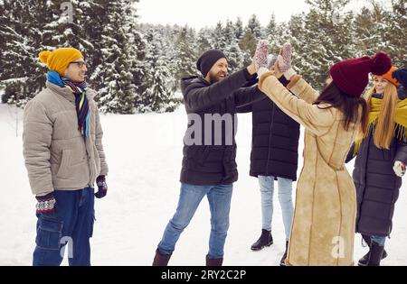 Die besten Freunde, umgeben von anderen Freunden, geben sich beim Spaziergang im Winter fünf hohe Freunde. Stockfoto