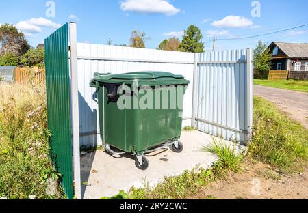 Grüner Plastikmüllbehälter im Freien im Dorf an sonnigen Sommertagen Stockfoto