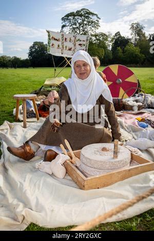 Wikingerfrau mahlt Grieß zu Mehl, während sie 1100 Jahre des alten „Cyty“ von Thelwall feiert und getrocknetes Brot hält Stockfoto