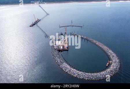 28. September 2023, Mecklenburg-Vorpommern, Prerow: Krane und Bagger werden für die Bauarbeiten am zukünftigen Inselhafen in der Ostsee eingesetzt. (Luftaufnahme mit Drohne) der Inselhafen soll den Schutzhafen auf der Halbinsel Fischland-Darß-Zingst ersetzen, der am 15.10.2023 endgültig geschlossen werden soll. Der Bau der vor etwas mehr als einem Jahr begonnenen künstlichen Insel sowie der 720 Meter lange Pier, der längste im Baltikum, wird voraussichtlich rund 42 Millionen Euro Kosten und für die Wassersportsaison 2024 in Betrieb genommen. Im Plan ist die Insel Har Stockfoto