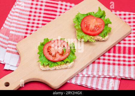 Reiskuchen-Sandwiches mit Tomaten und Salat auf Holzbrett. Einfaches Frühstück. Diät-Essen. Schnelle und gesunde Sandwiches. Knäckebrot mit leckerer Füllung. Gesunder Ernährungs-Snack Stockfoto