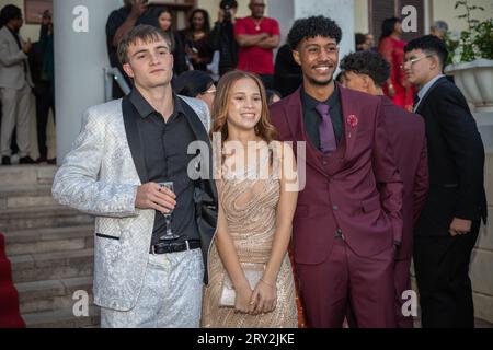 In einem Abschlussball aus nächster Nähe posieren drei multirassische Freunde mit Zuschauern und halten einen lebendigen und fröhlichen Moment bei der Veranstaltung fest Stockfoto