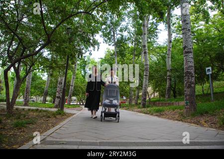 Peking, China - 6. Mai 2023: Zwei Damen schlendern mit ihren Kinderwagen im Park. Stockfoto