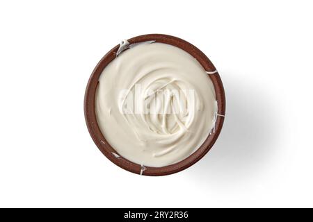 Griechischer Joghurt Sauerrahm in einer braunen Tonschale isoliert auf weißem Hintergrund. Draufsicht mit Kopierbereich. Stockfoto