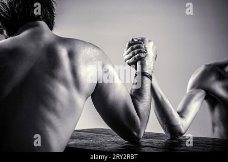 Arme, die dünne Hand wringen, großer, starker Arm. Zwei Männer haben Armringen geschlossen, stark und schwach, ungleiche Übereinstimmung. Schwarz-weiß Stockfoto