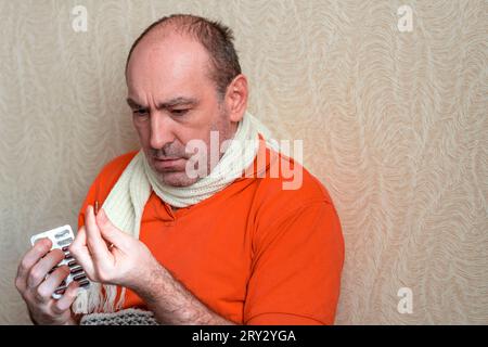 Ein kranker Mann hält seine Hand über den Kopf. Das Medikament, die Behandlung. Konzept krank, ungesund. Übelkeit und Müdigkeit. Mann fühlt sich schlecht. Der Patient hält Stockfoto