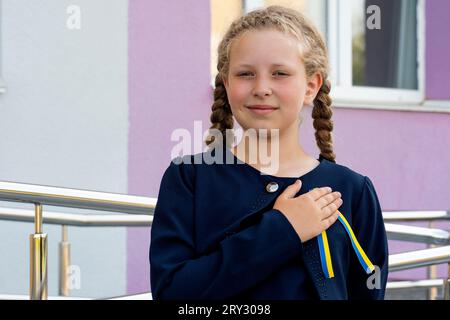 Schulmädchen hält Hand auf Herz! patriot, stolzes Mädchen, das Konzept des Stolzes. Das Konzept des Stolzes als alles andere, Patriotismus . Nationale Farben der Ukraine, Stockfoto