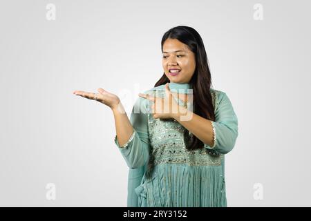 Südasiatische nepalesische junge Frau lächelt in einem Kurthi, der Gesten und Namaste gibt Stockfoto