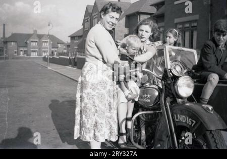 1950er Jahre, historisch, draußen in einer Vorstadtstraße versammelten sich zwei Mütter mit Tbeir-Kindern neben und auf einem Harley Davidson Motorrad und Beiwagen der Ära, Oldham, England, Großbritannien. Stockfoto