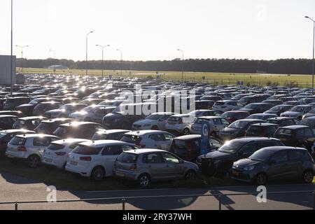 Flughafenparkplatz P5 am Flughafen Eindhoven, Niederlande, mit vielen geparkten Autos, die in der Sonne glitzern, in der Nähe der Landebahn Stockfoto