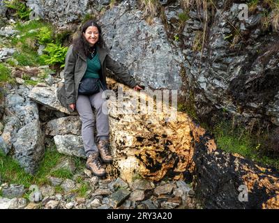 Lächelnde Frau, die auf den Moine Thrust zeigt, North West Highlands Geopark, Knockan Crag, Schottland Stockfoto