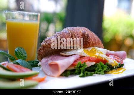 Frisches Sandwich-Croissant mit rotem Fisch, Weichkäse und Grünzeug. Frühstück Croissants Sandwiches mit Lachs, Gurke, Frischkäse und Rucola auf einem Tisch. Stockfoto