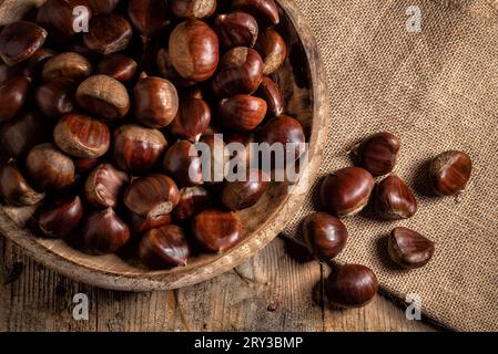 Kastanien in einem Holzteller auf einem Sackleinen-Sack Stockfoto