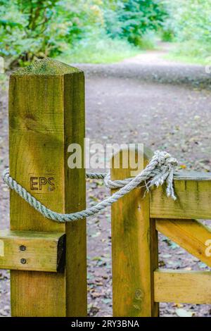 Ein hölzernes Tor, das mit einem geknoteten Seil auf einem Landweg verschlossen wurde. Konzept Wohlbefinden, Gesundheit, Wandern, Landschaft, Bewegung, geschlossen, geschlossen, offen, symbolisch Stockfoto