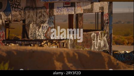 Verlassene Hülle einer stark verwüsteten und mit Graffiti getaggten Gas- und Tankstelle mit I-15-Verkehr im Hintergrund. Stockfoto