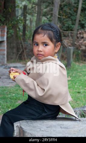 Unschuld in Not: Porträt eines südamerikanischen indigenen Kindes, das eine Kartoffel isst und mit einer Mischung aus Neugier und Vorsicht auf die Kamera blickt Stockfoto