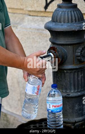 Man füllt Wasserflaschen am alten traditionellen öffentlichen Trinkwasserbrunnen Stockfoto