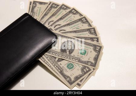 Foto von zwei Dollarscheinen auf weißem Hintergrund mit Kopierraum neben einer Brieftasche. Stockfoto