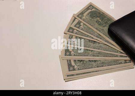 Foto von zwei Dollarscheinen auf weißem Hintergrund mit Kopierraum neben einer Brieftasche. Stockfoto