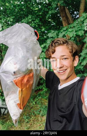 Porträt eines glücklichen Teenagers, der Müllsack mit Plastik zeigt Stockfoto