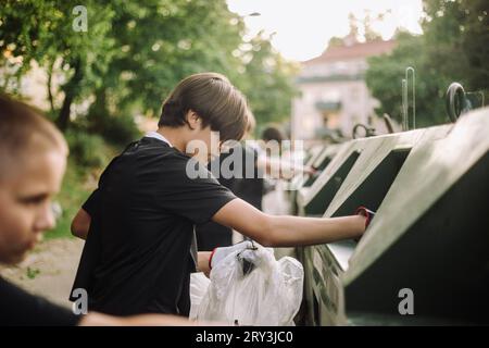 Teenager, der Müll in den Abfalleimer legt Stockfoto