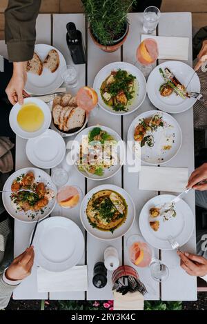 Direkt über dem Schuss von männlichen und weiblichen Seniorenfreunden, die Essen zusammen mit Getränken auf dem Tisch im Restaurant essen Stockfoto