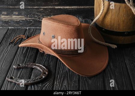 Cowboyhut, Lasso und Hufeisen auf Holzhintergrund Stockfoto