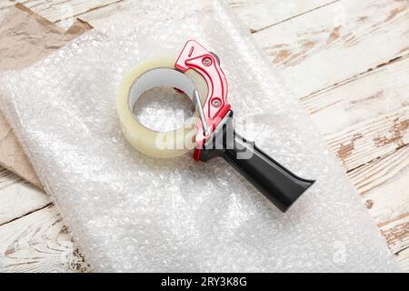 Abroller für Verpackungsband und Luftpolsterfolie auf Holzhintergrund Stockfoto