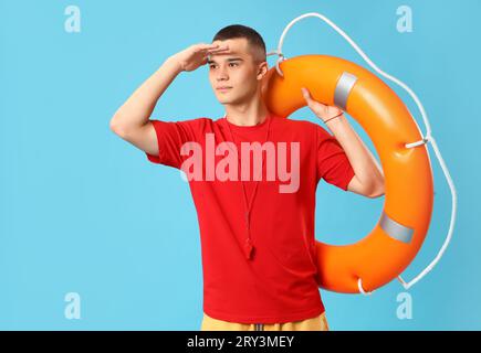 Männlicher Rettungsschwimmer mit Ringboje auf blauem Hintergrund Stockfoto