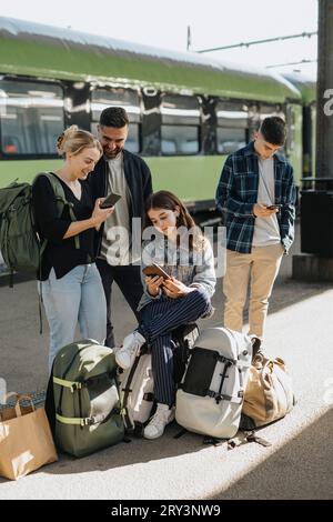 Familie nutzt Smartphones, während sie am Bahnhof auf den Zug wartet Stockfoto