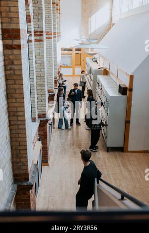 Hochwinkelansicht männlicher und weiblicher Schüler durch Schließfächer im Schulkorridor Stockfoto