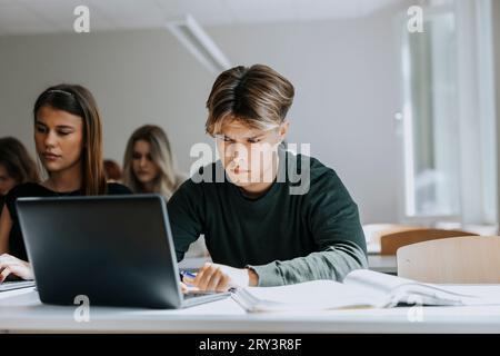 Teenager, der im Klassenzimmer auf den Laptop starrt Stockfoto