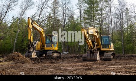 CROW WING CO, MN - 10. MAI 2023: Abgewinkelte Ansicht zweier gut gebrauchter Komatsu-Bagger, die auf einer Baustelle eines zukünftigen neuen Wohngebäudes geparkt sind Stockfoto