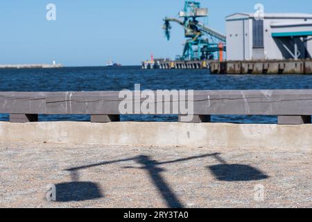 Blauer Güteraufzug und Industriegebäude auf einer schwimmenden Plattform im Meer und klarer blauer Himmel im Hintergrund. Im Vordergrund ein hölzerner fenc Stockfoto