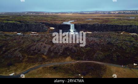 Drohnenaufnahme des Oxarafoss-Wasserfalls in island, wunderschöne massive Kaskade, die von Klippen abläuft. Isländische Natur und Landschaft mit Fluss, der aus Hügeln fließt. Zeitlupe. Stockfoto