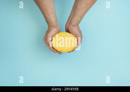 Die Hände eines Mannes halten einen Schwamm Stockfoto