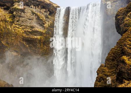 Polare Skgafoss fallen von Klippen herunter und bilden eine spektakuläre isländische Landschaft. Massiver nordischer Wasserfall, der von braunen Klippen abfließt, majestätische Eislandschaft in island. Stockfoto