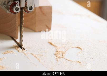 Zimmermannswerkzeuge auf Holztisch mit Sägemehl. Bandsäge zum Schneiden einer komplizierten Form in einem Stück Holz. Stockfoto