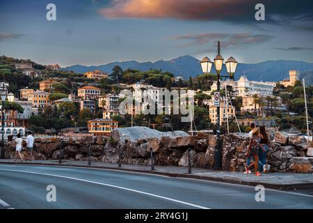 Santa Margherita Ligure in der Abenddämmerung, ein traumhaft ruhiges Foto mit beleuchteten Straßenlampen und der goldenen Sonne auf den Gebäuden am Berghang Stockfoto