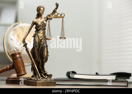 Figur der Lady Justice, Gavel, Globus und Notizbücher auf dem Tisch drinnen, Platz für Text. Symbol der gerechten Behandlung nach dem Gesetz Stockfoto