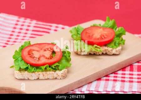 Reiskuchen-Sandwiches mit Tomaten und Salat auf Holzbrett. Einfaches Frühstück. Diät-Essen. Schnelle und gesunde Sandwiches. Knäckebrot mit leckerer Füllung. Gesunder Ernährungs-Snack Stockfoto